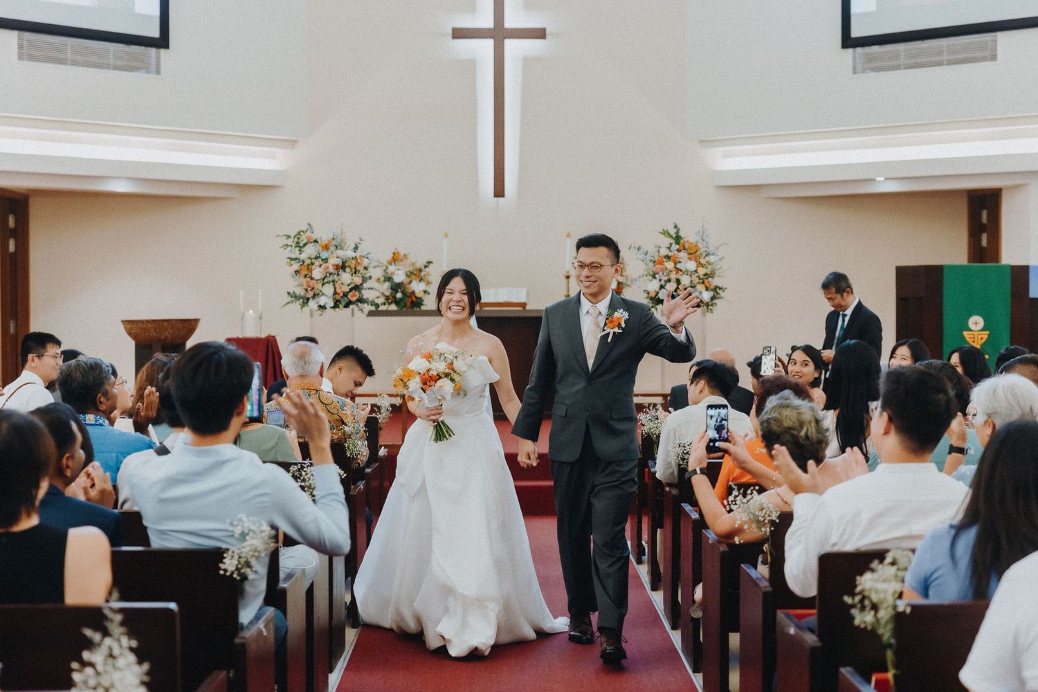 Church wedding ceremony with guests watching the couple exchange vows under a cross.