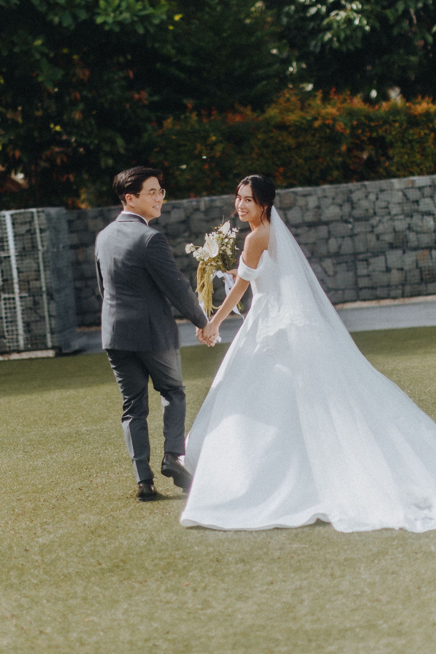 Joyful moment captured during outdoor wedding photos on green lawn.