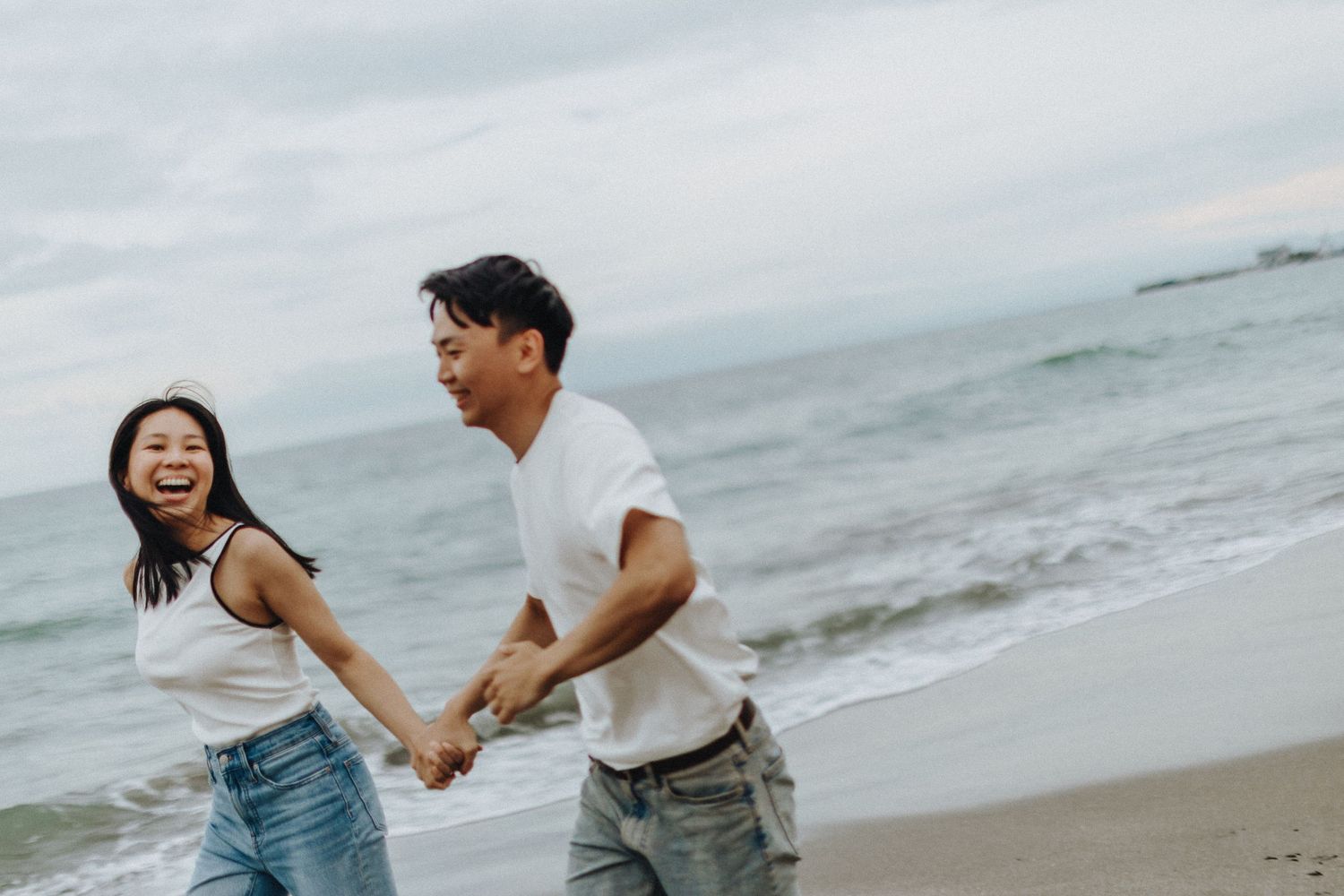 Couple playing and running together on a misty beach shoreline.