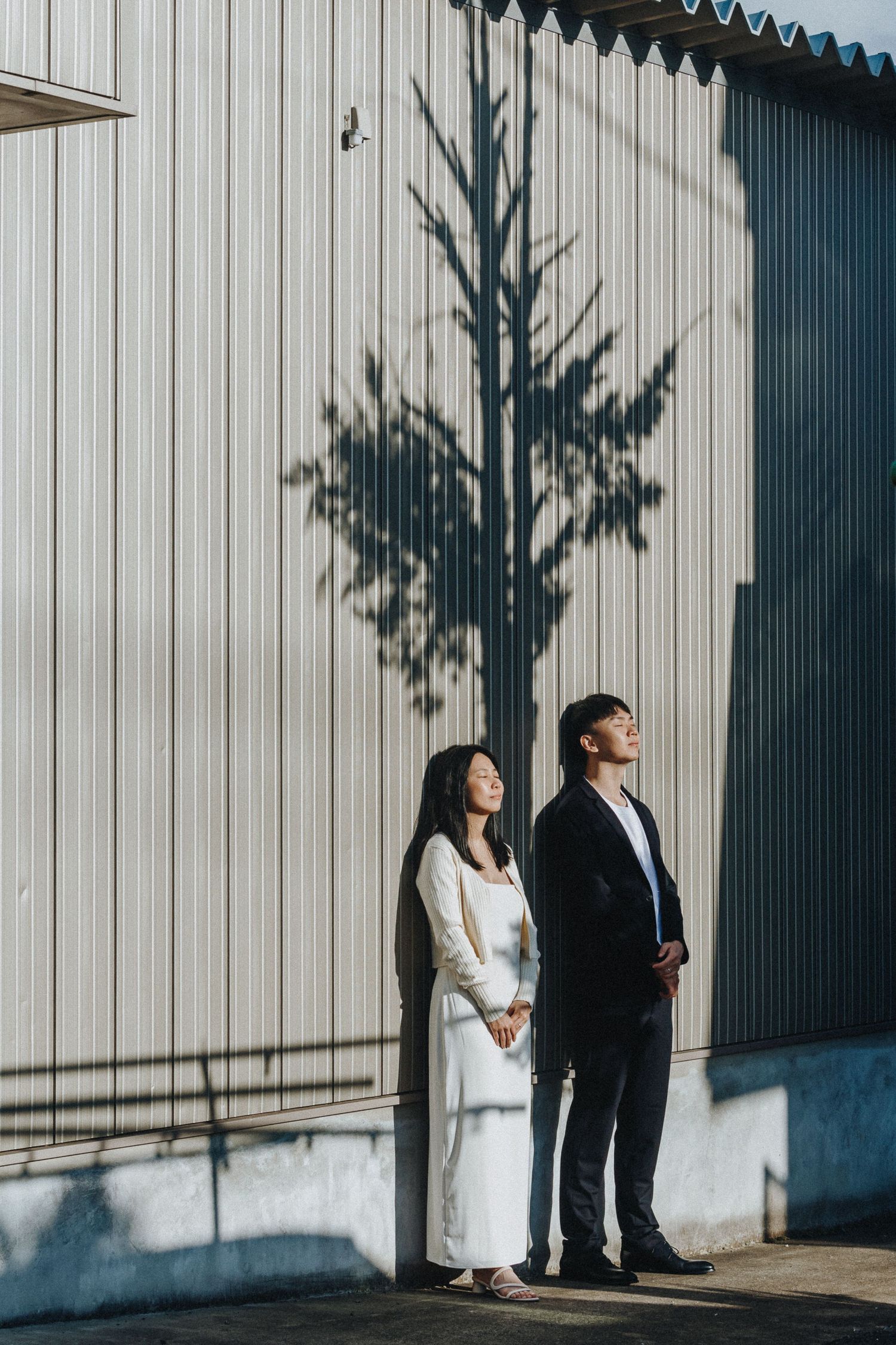 Minimalist wedding portrait against white walls with dramatic shadows.
