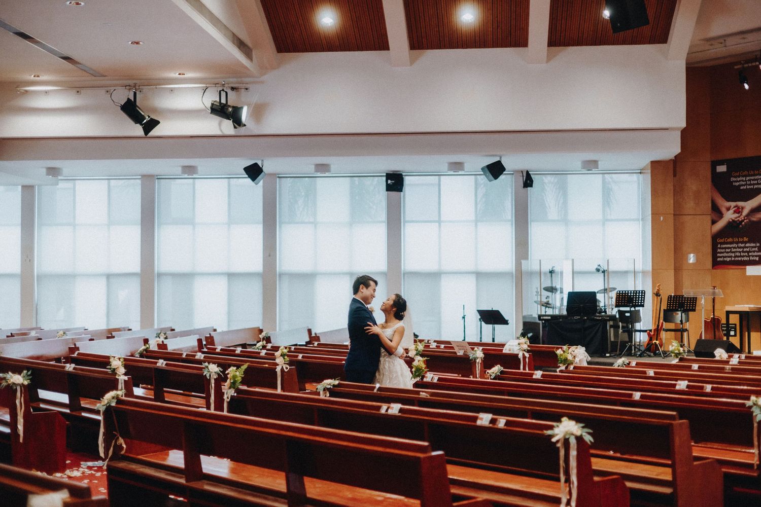 A wedding ceremony in a modern church with wooden pews and large windows.