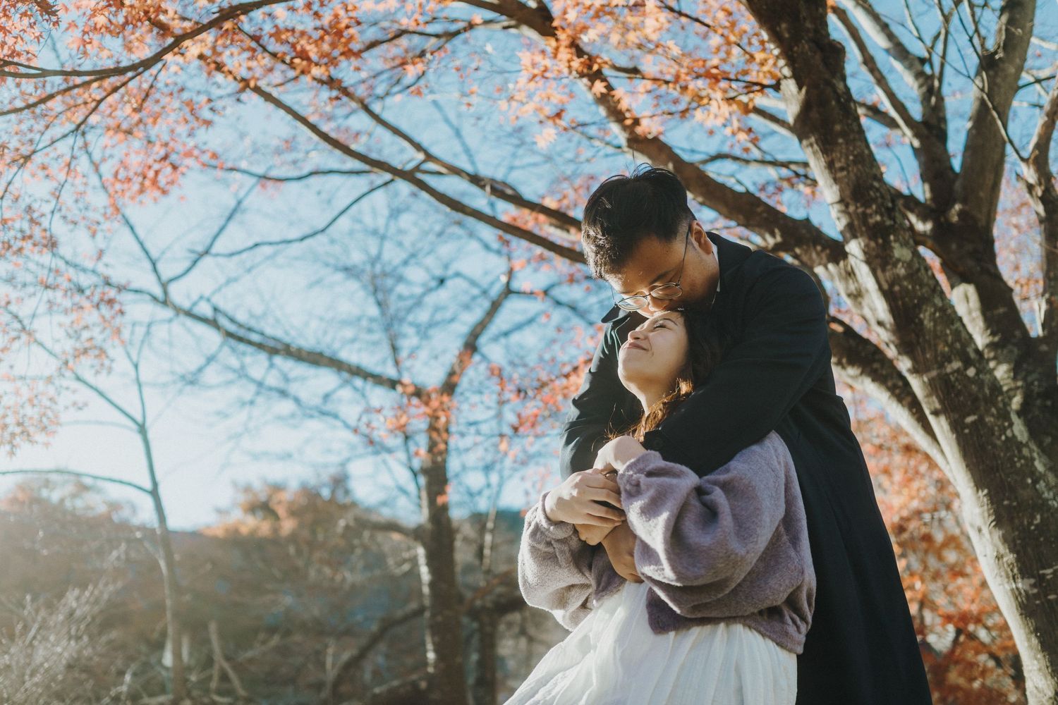 Romantic moment under blooming cherry blossoms with soft natural lighting.