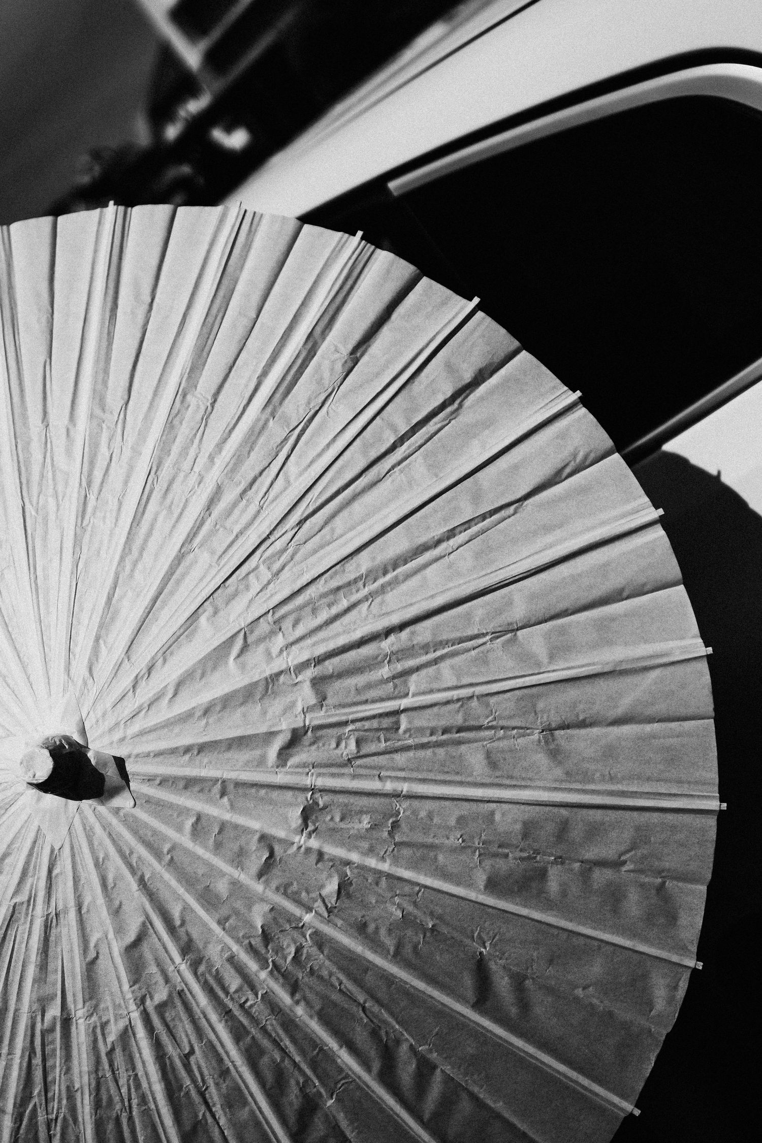 Black and white close-up of a traditional paper parasol showing radiating pattern details.