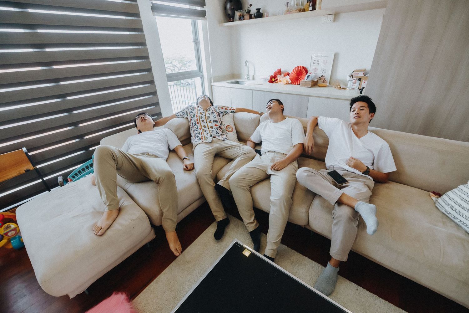 Three guests relaxing casually on a white couch in a modern living room setting.