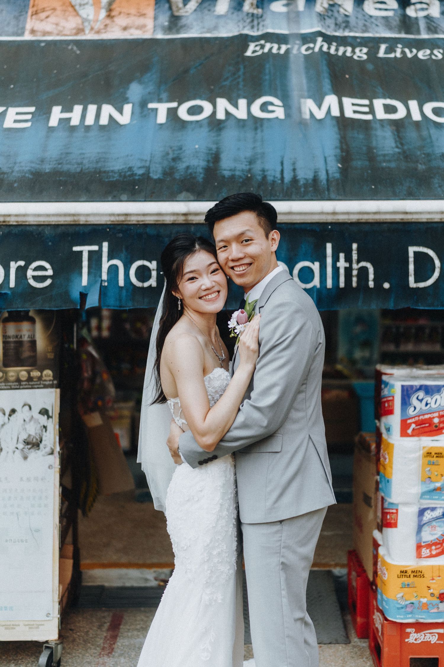 A couple poses lovingly outside Hin Tong Medical store in their wedding attire.
