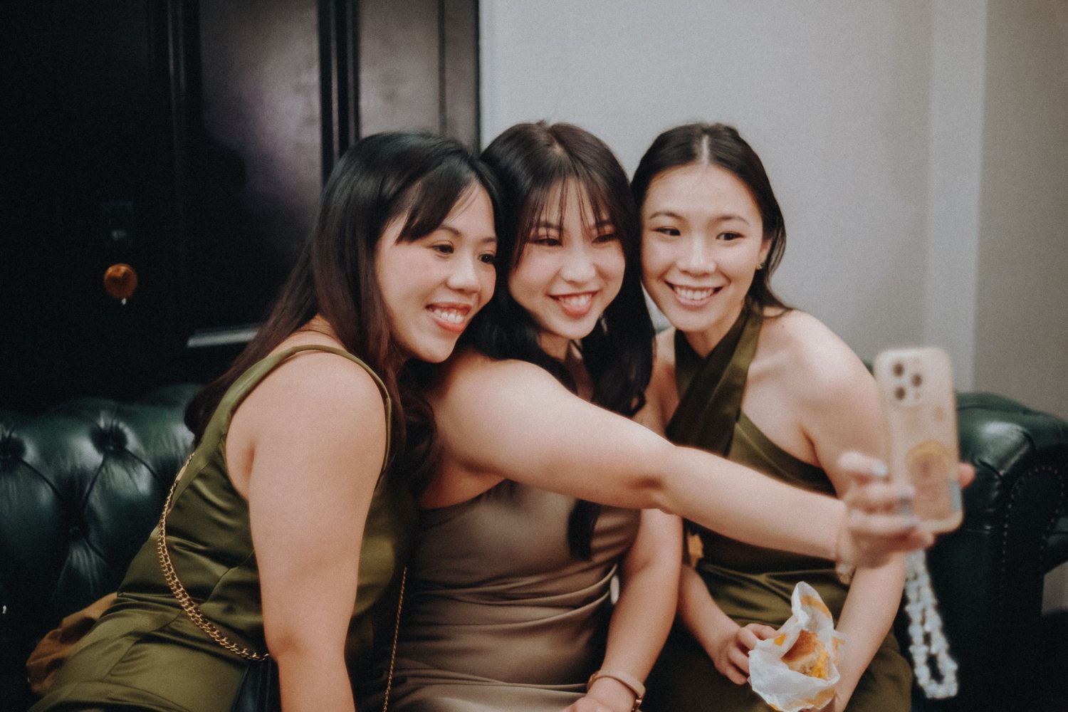 A group of friends laugh and share drinks together in a dimly lit social gathering space.