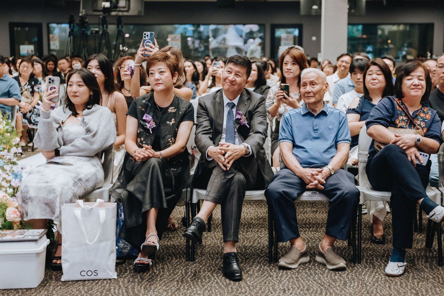 Wedding guests seated in rows watching ceremony in modern indoor venue.