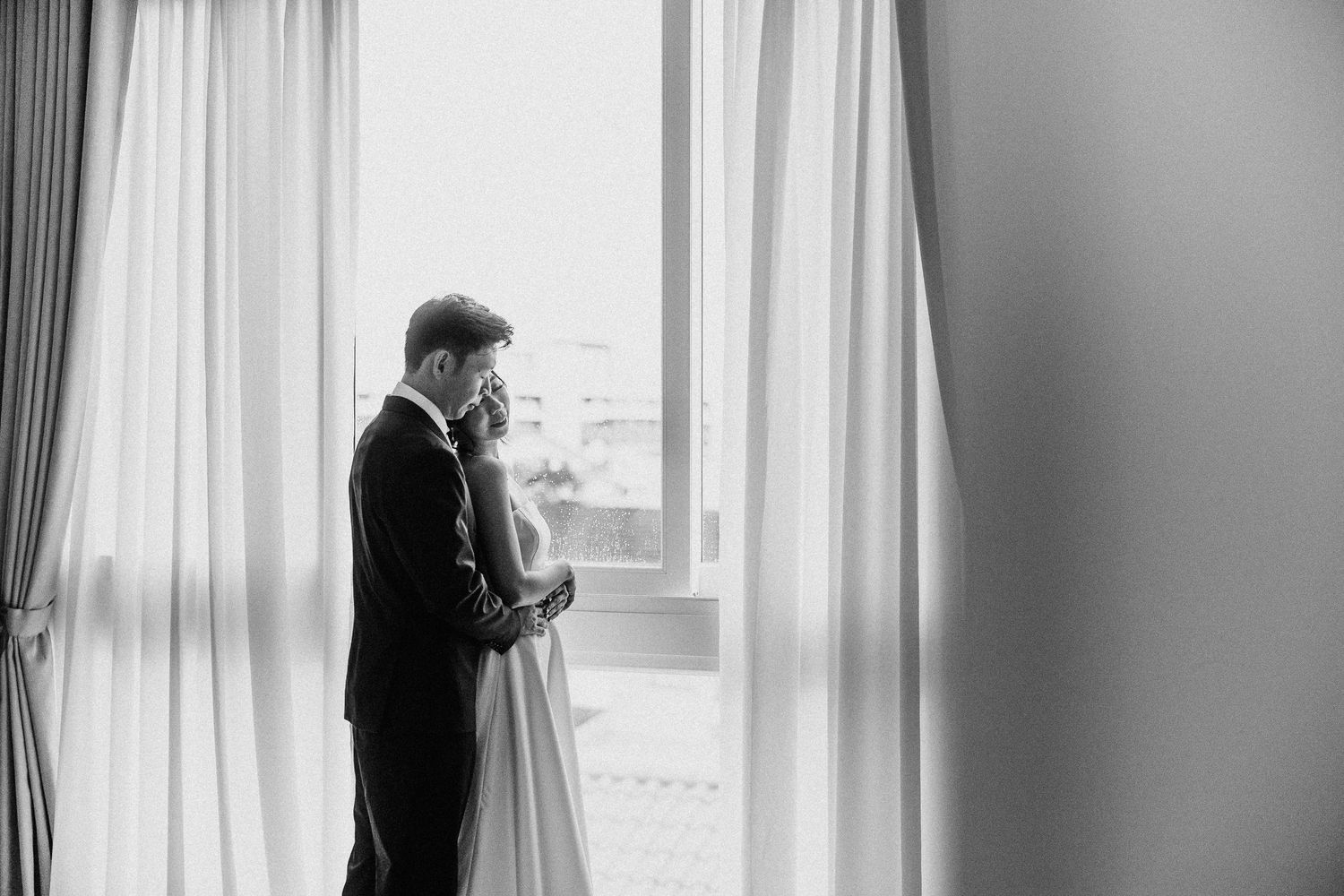 A series of black and white wedding photographs showing intimate moments and preparations by a window.