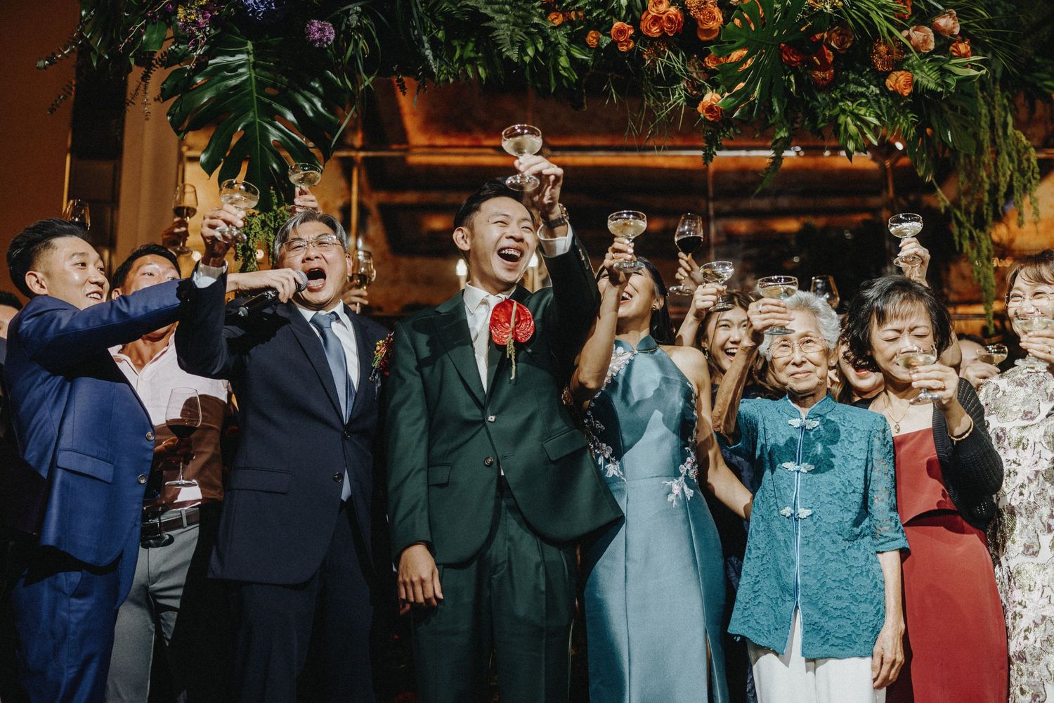 Wedding party celebrating with champagne toast under floral decorations.