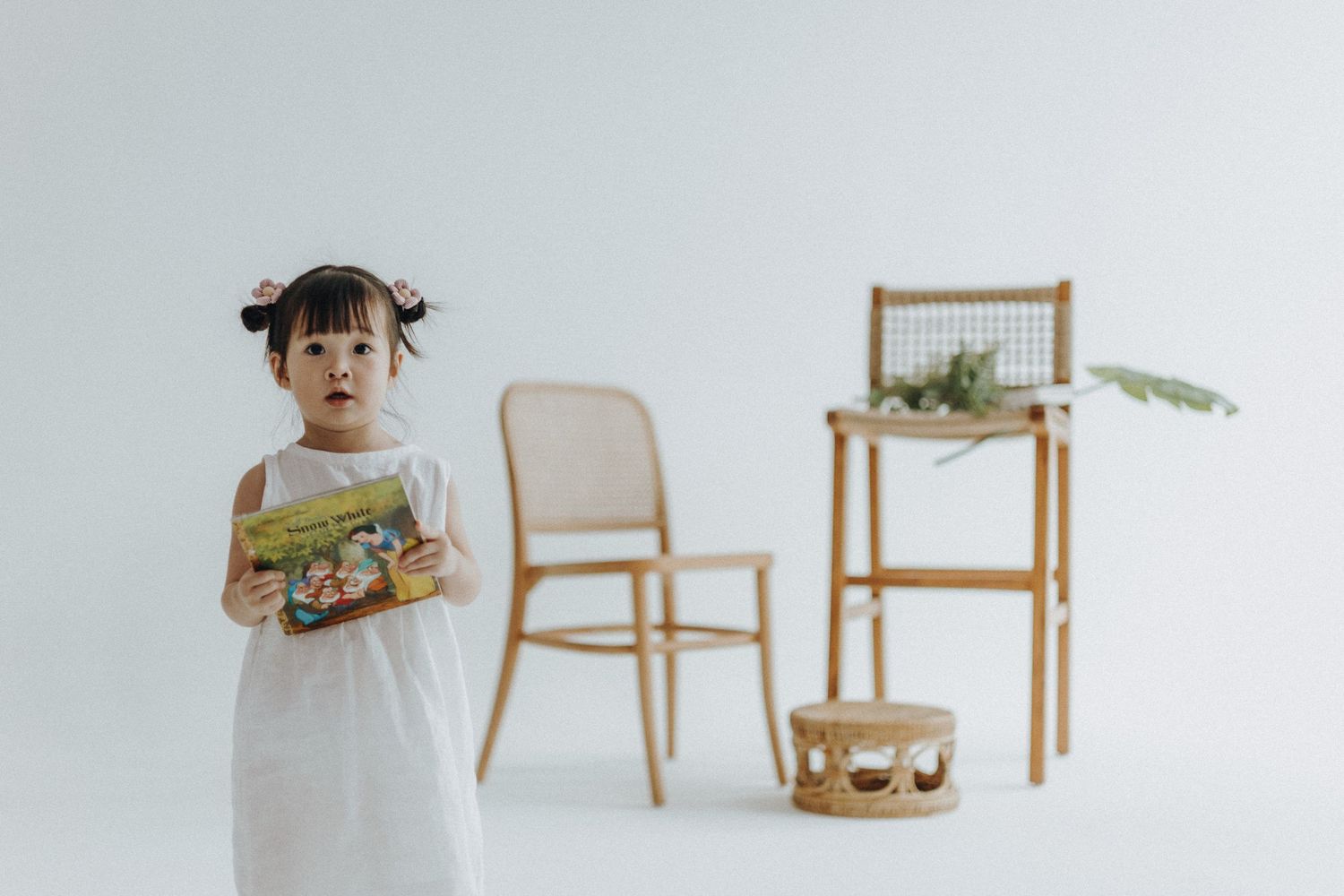 A minimalist room setup with wooden chairs and a small table against a white backdrop.