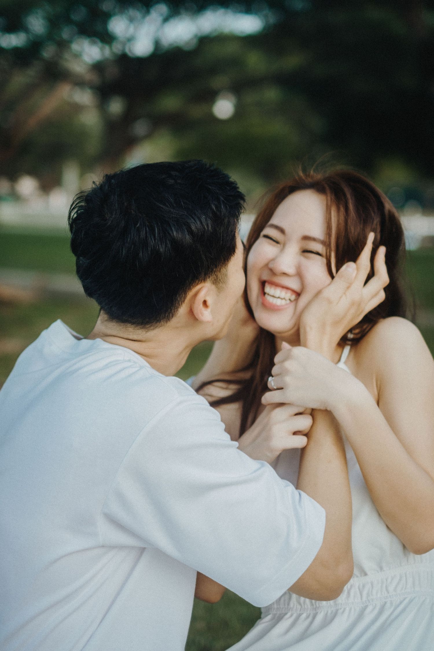 Playful outdoor couple photography sequence showing tender moment in white clothing against natural background.