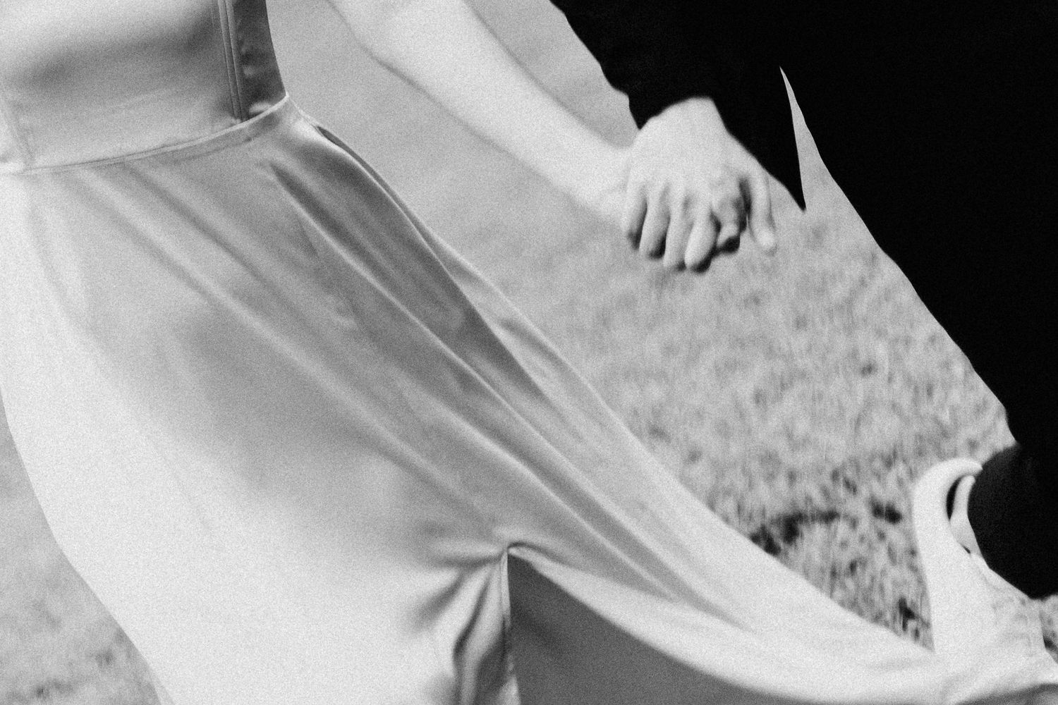 Black and white close-up photograph showing hands holding an open book or paper against a blurred background.