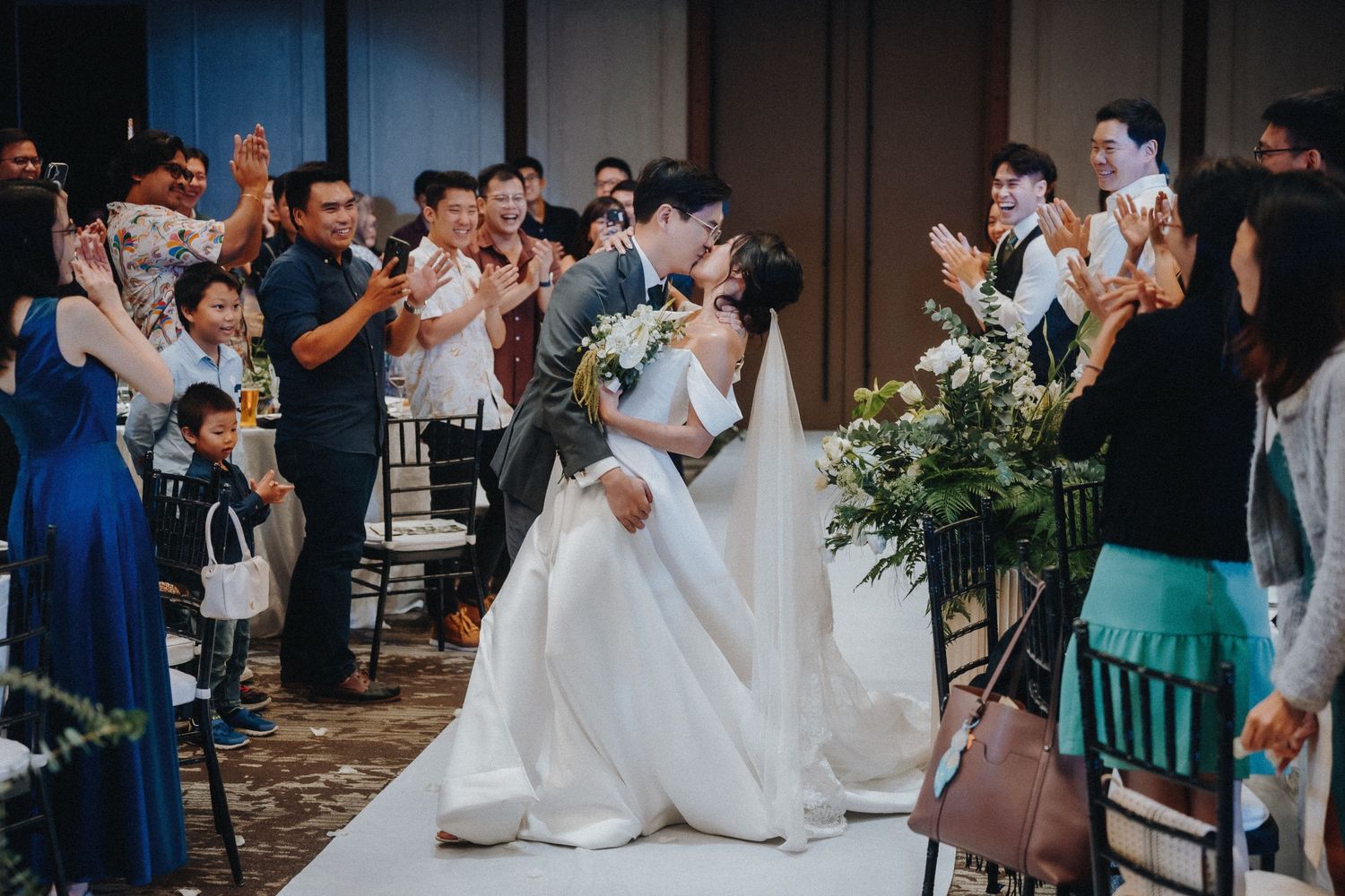 Wedding reception guests celebrate and take photos as the newlyweds dance in a ballroom setting.