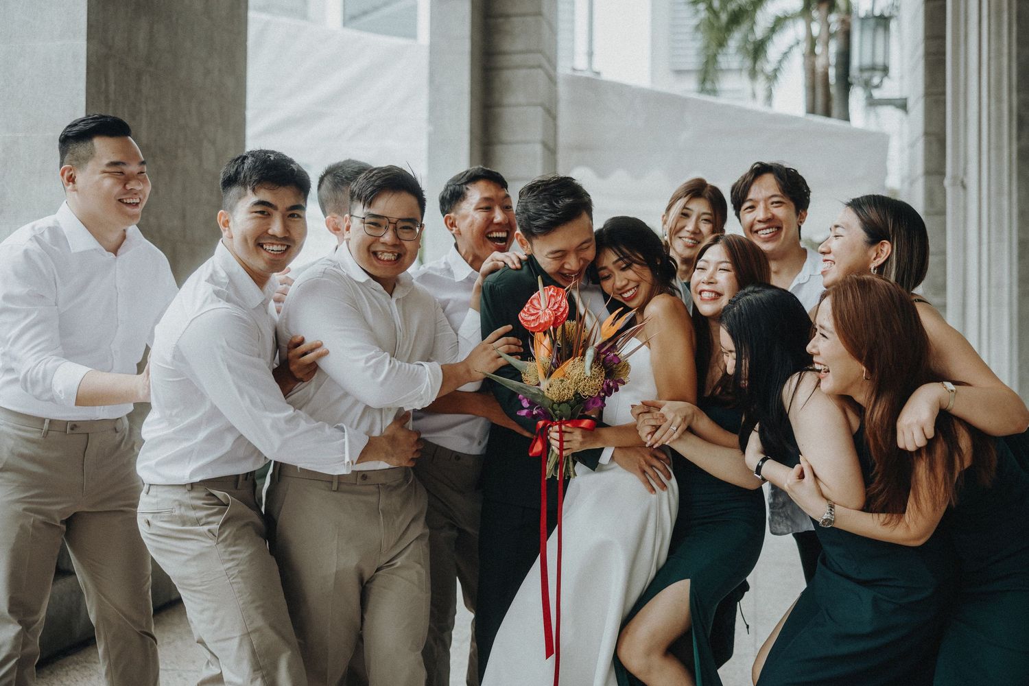 Joyful wedding party members laughing and celebrating together outdoors.