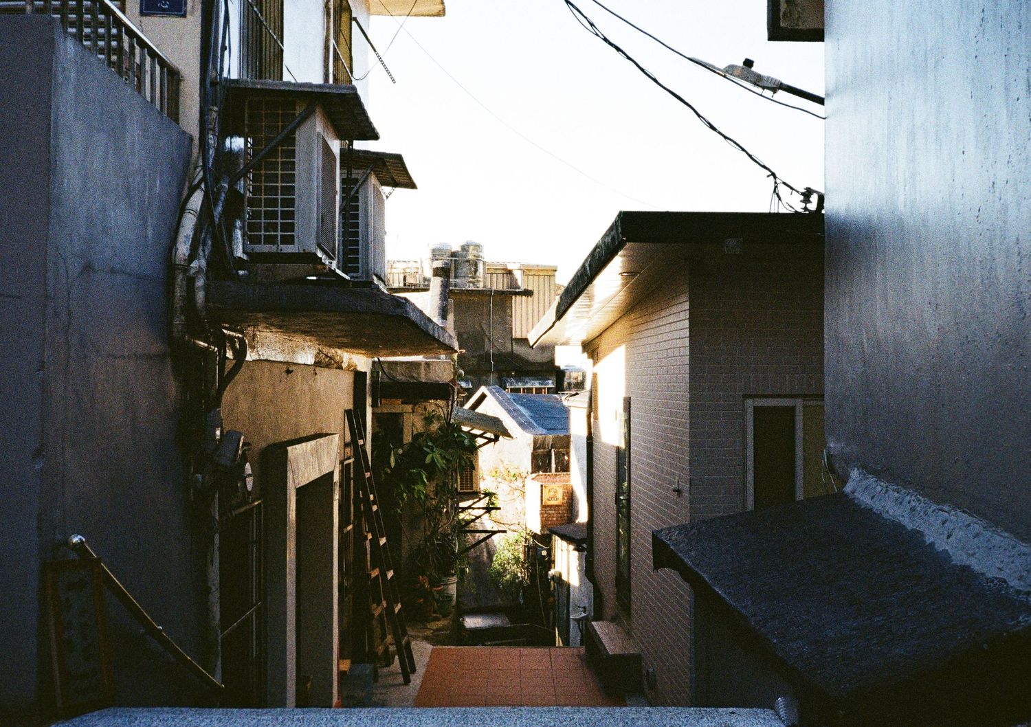 Dark residential alleyway in Japan with narrow streets and traditional architecture lit by evening light.