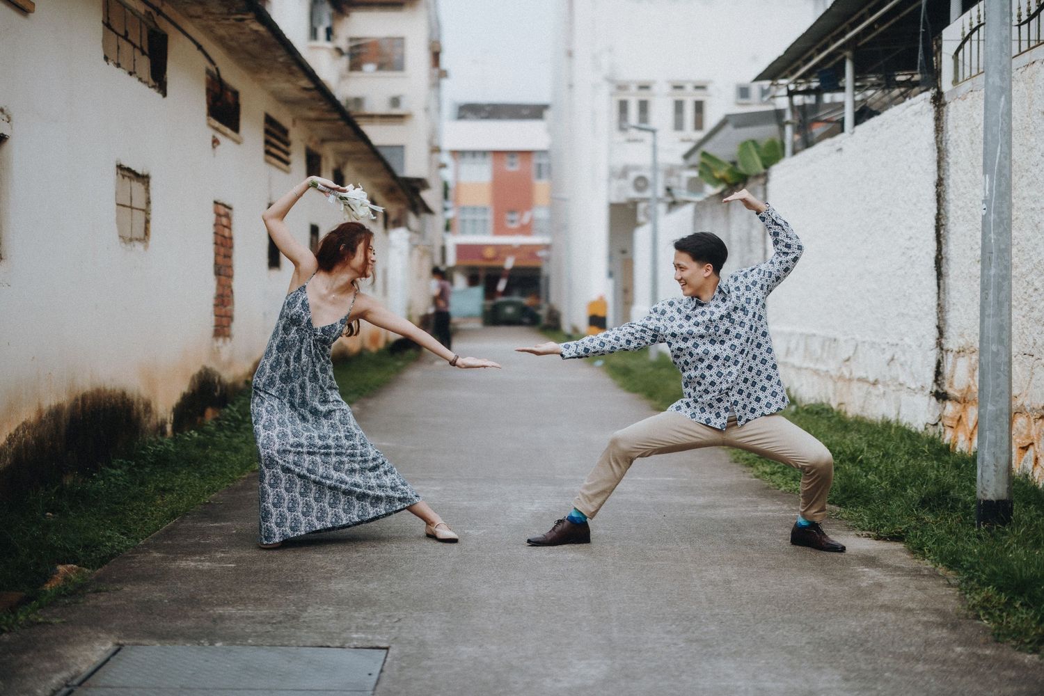Playful couple dancing and posing in a narrow urban street between buildings.