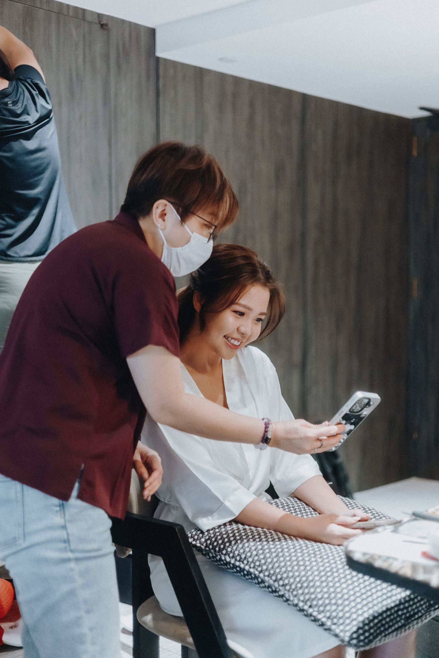 Behind-the-scenes wedding preparation showing two people looking at a phone while getting ready.