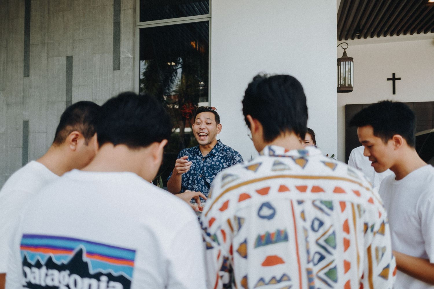 Friends in patterned shirts share a laugh and conversation together outside a building.
