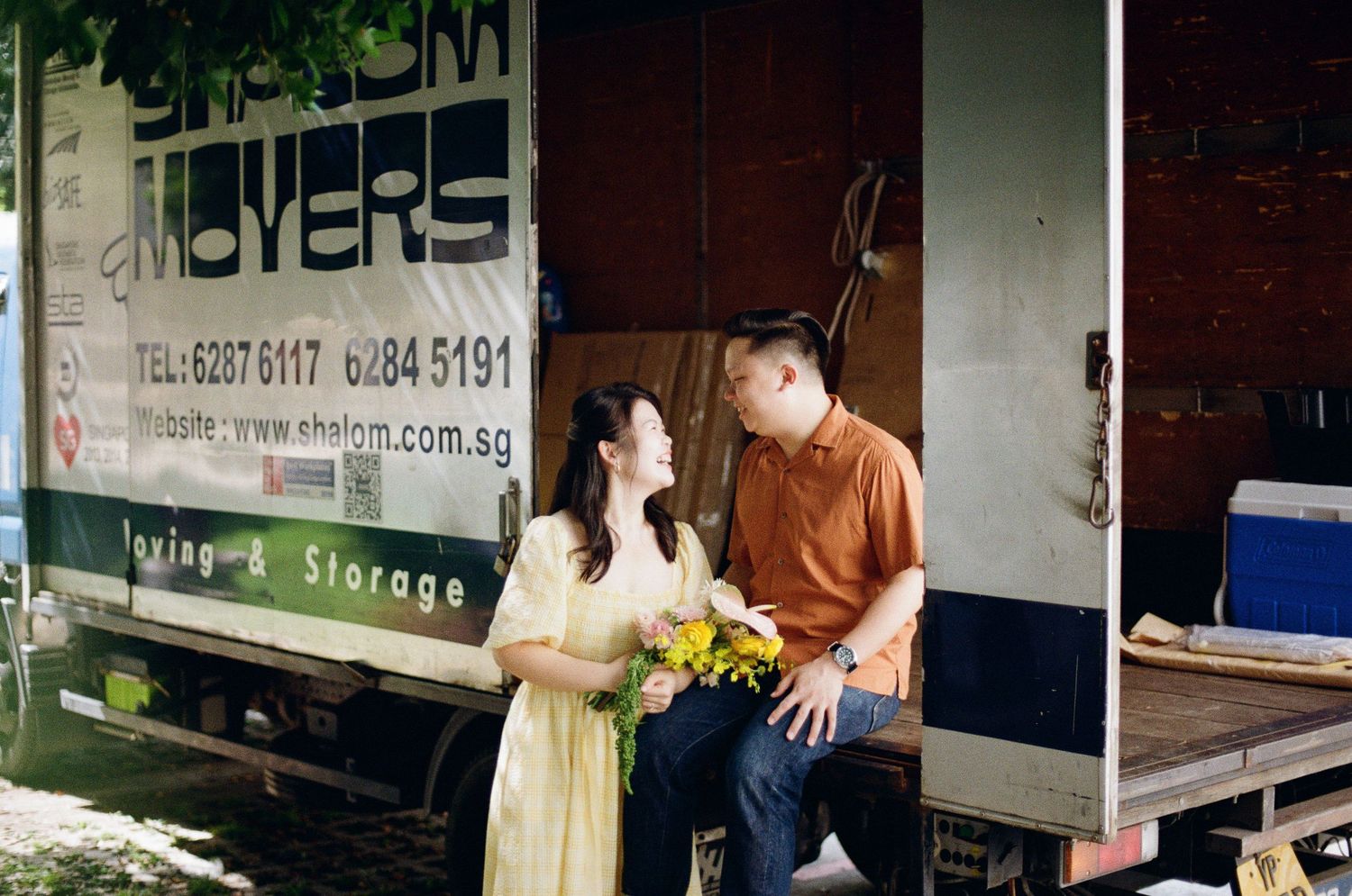 A couple sharing a sweet moment by a delivery truck in casual attire.