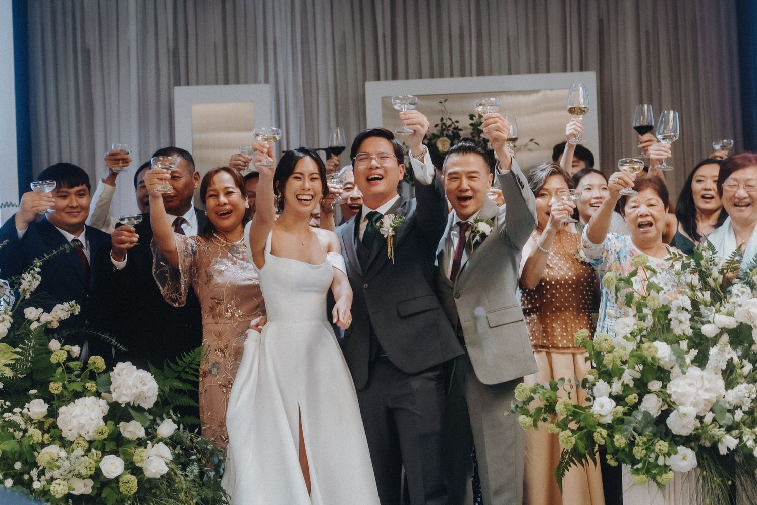 Wedding celebration with white floral arrangements and elegant drapery in the background.