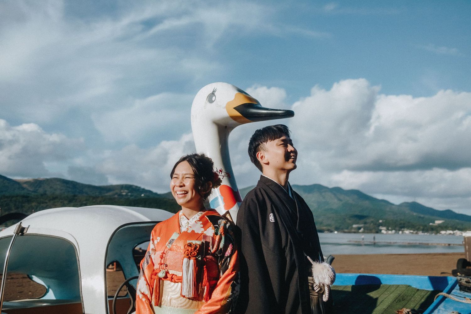 Couple in traditional Japanese attire enjoying a scenic mountain lake view.