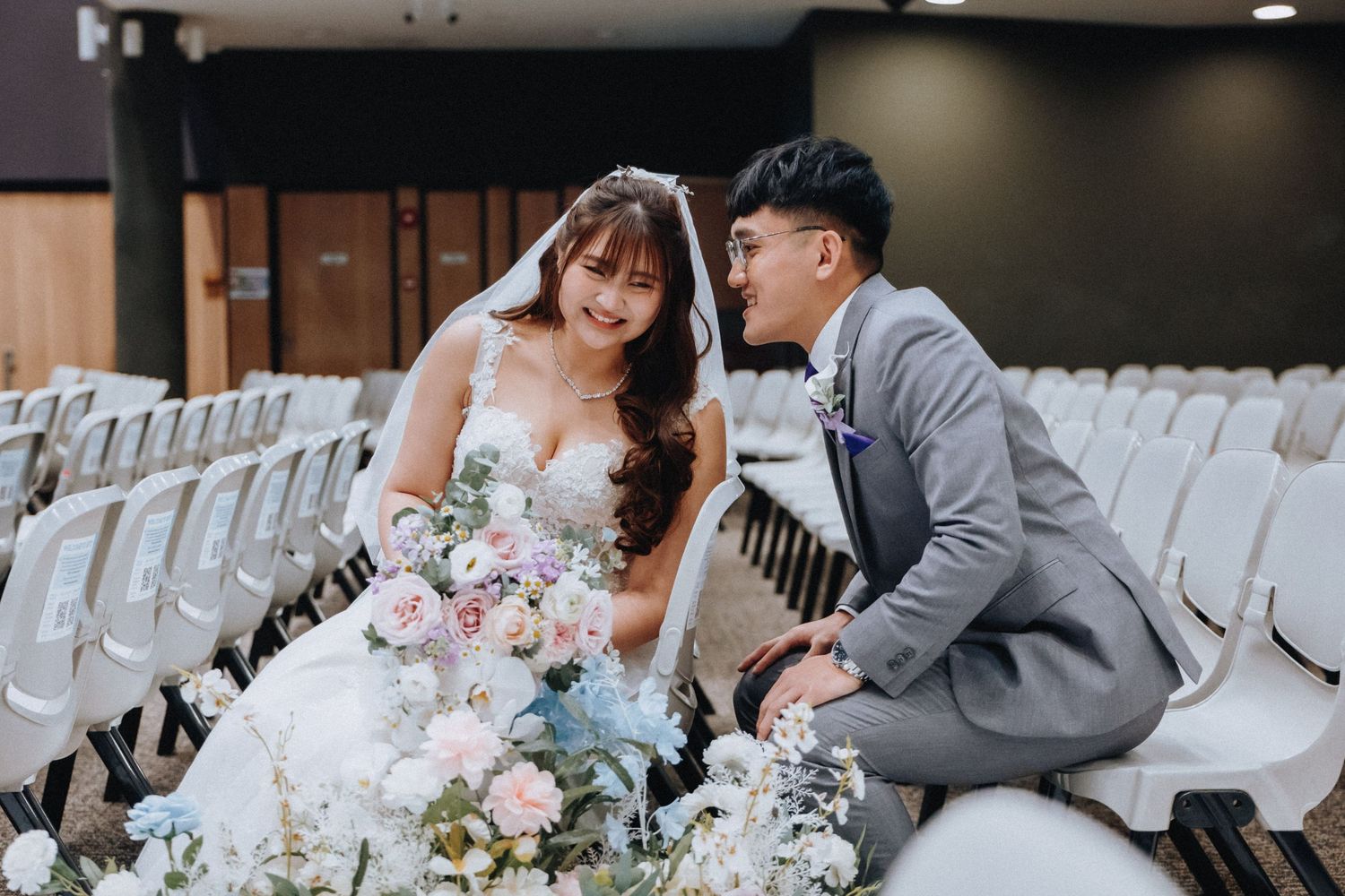 A couple shares an intimate moment during their outdoor garden wedding ceremony surrounded by white chairs and floral decor.