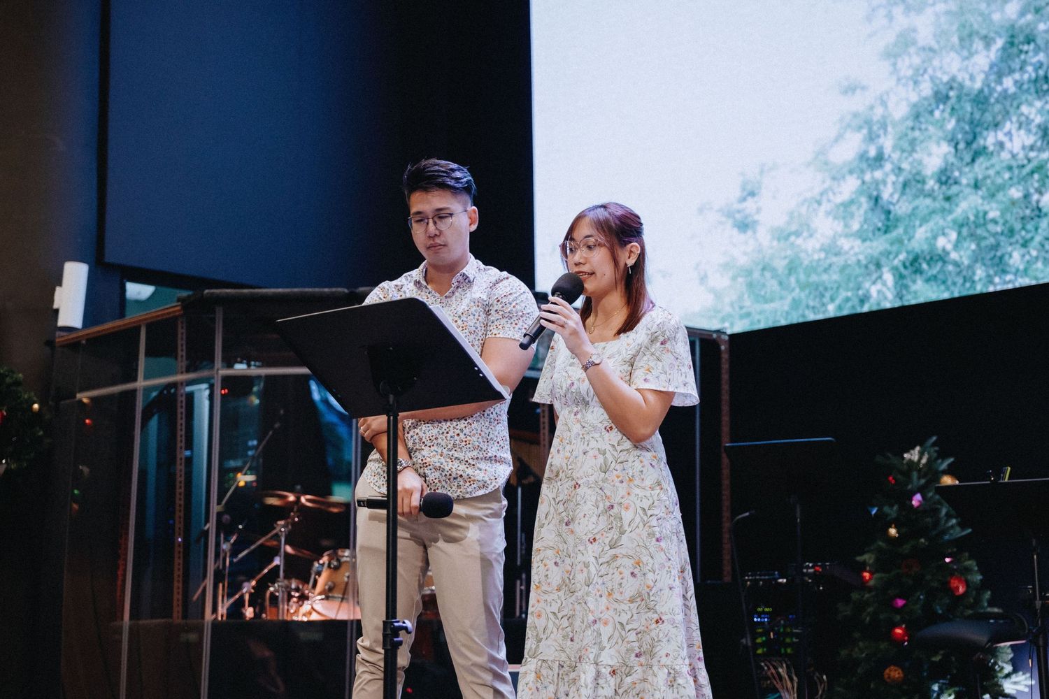 Two performers singing at microphone stands during a wedding celebration.