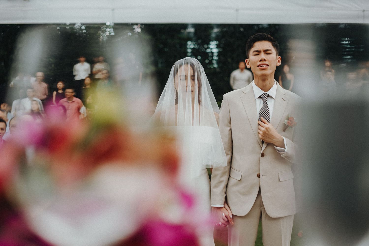 Elegant wedding portrait session in a garden setting with pink florals in the foreground.