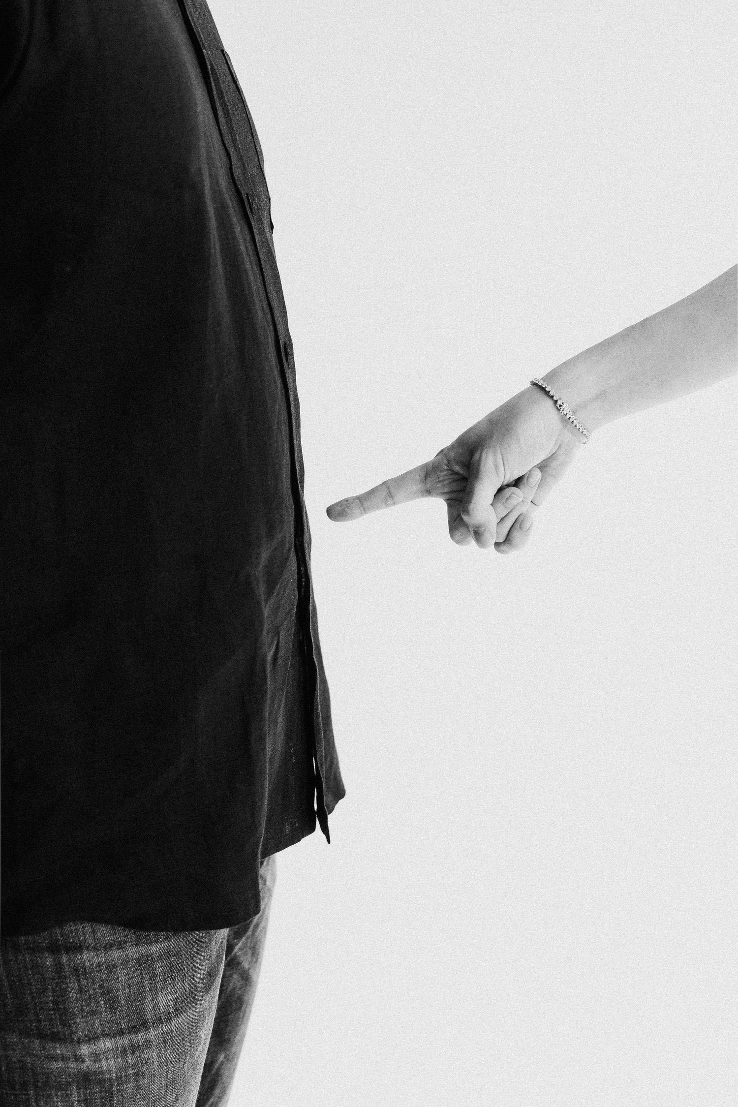 Minimalist black and white photo showing a pointing hand gesture against a plain background.