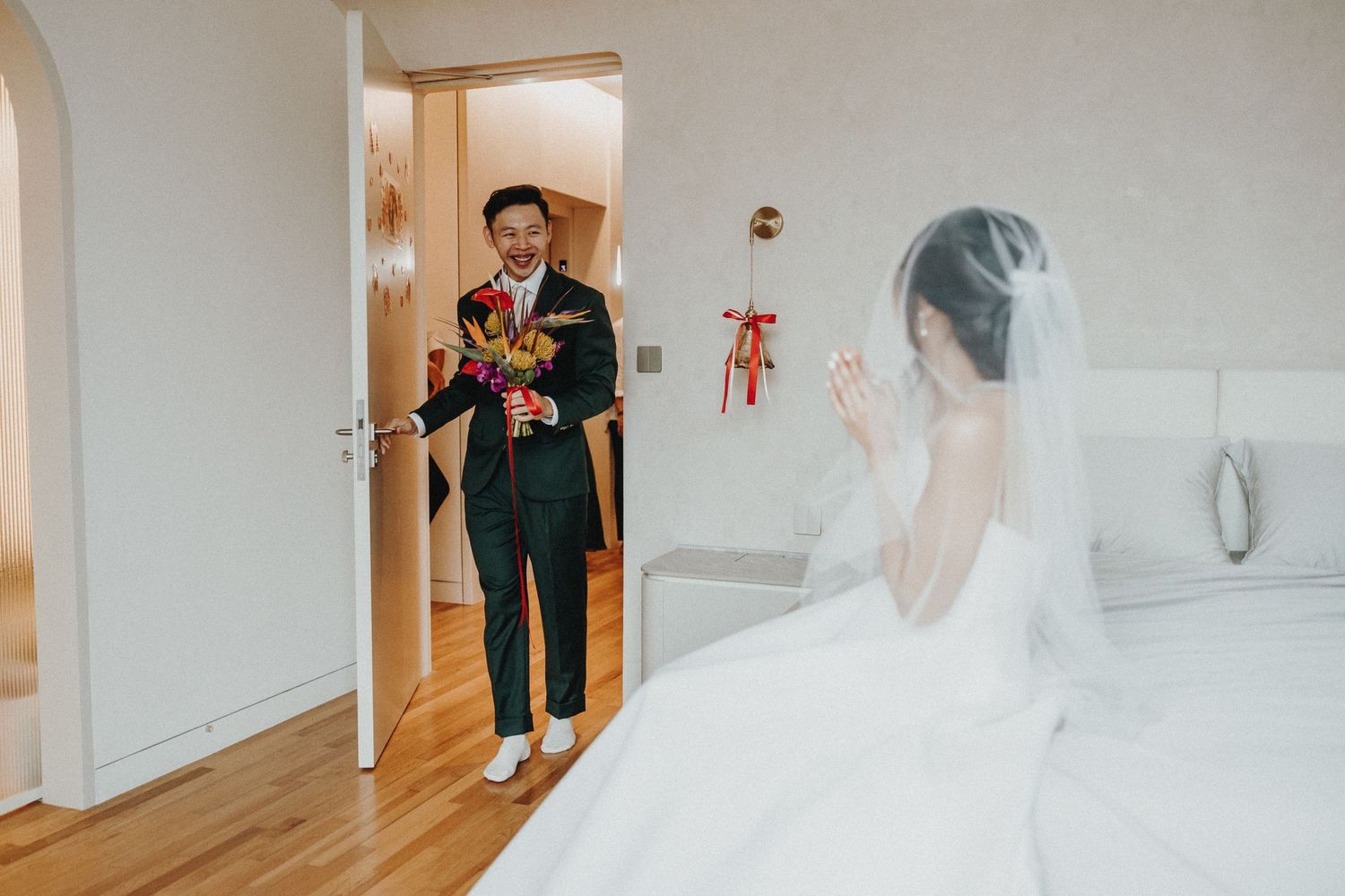 A romantic first look moment in a brightly lit hallway as a bride in white gown greets her partner.