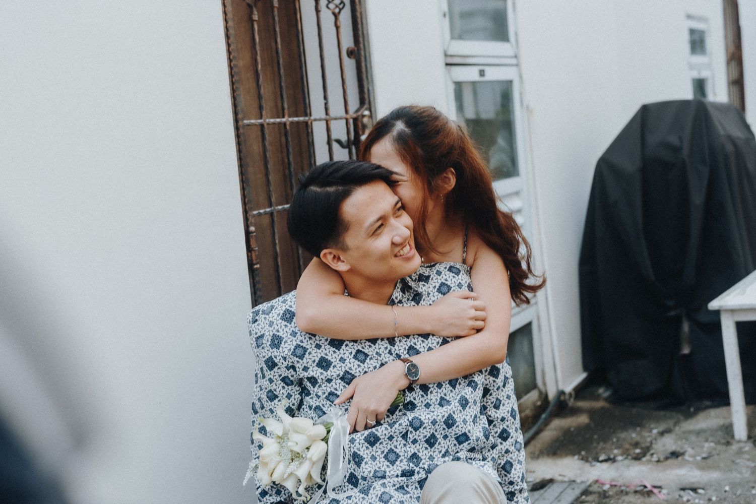 A couple shares a tender embrace while wearing matching floral print outfits outdoors.