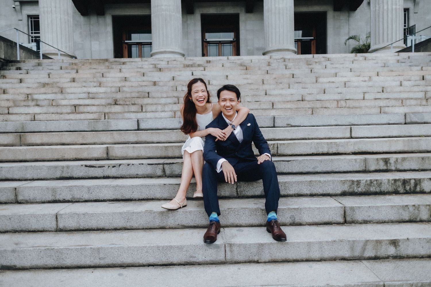 Engagement portrait of couple sitting together on grand stone steps.