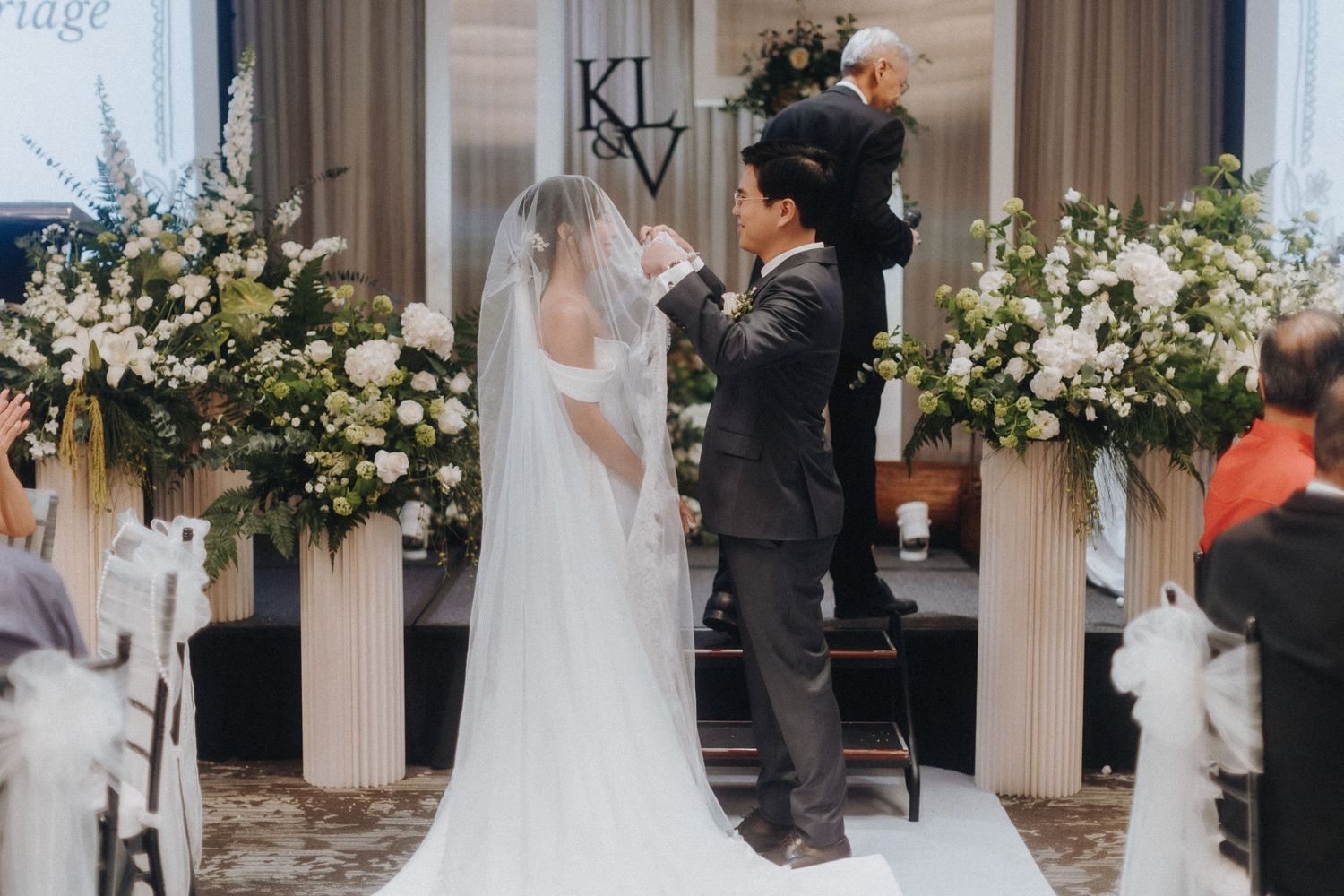 A wedding ceremony in progress with elegant white floral arrangements decorating the venue.
