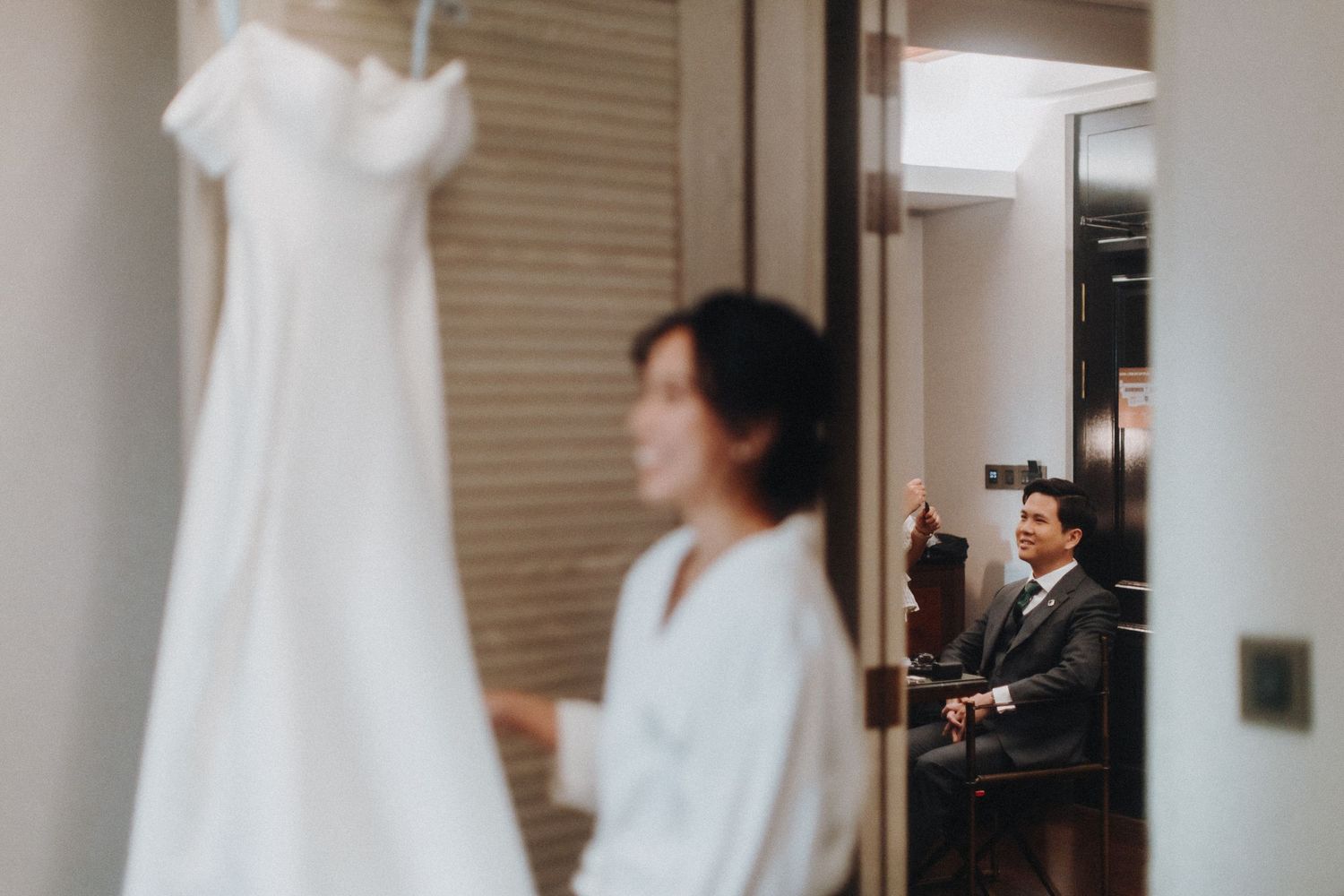 A row of white wedding dresses displayed on hangers in a bridal shop fitting room.