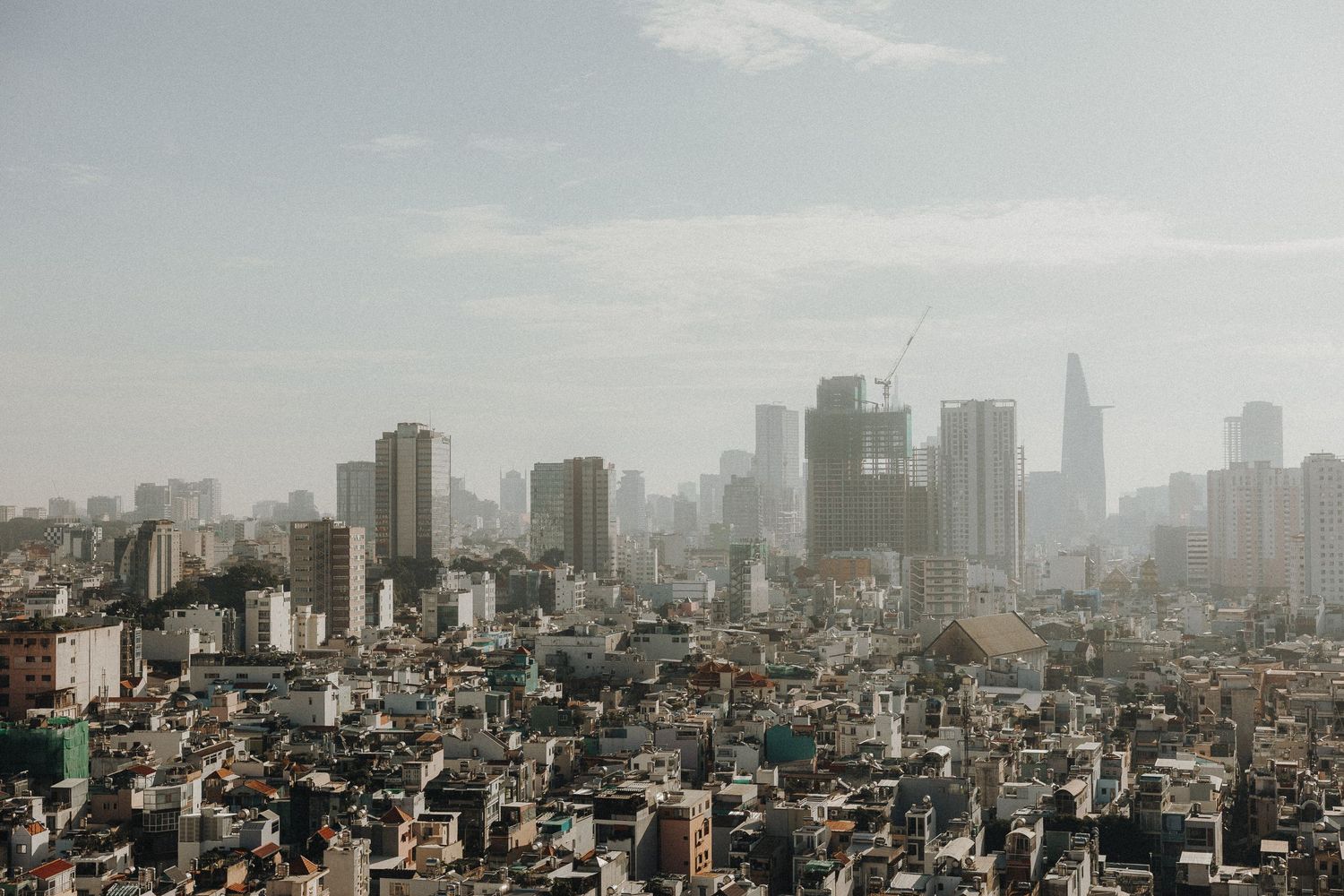 An expansive aerial cityscape view of Tokyo's urban sprawl with tall buildings and skyscrapers under a cloudy sky.