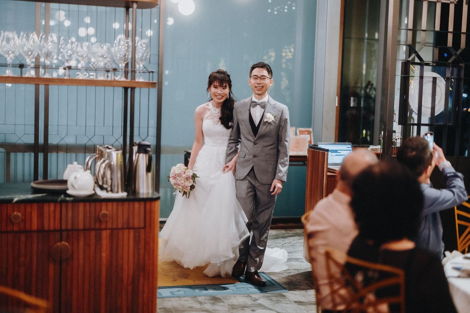 Wedding reception venue decorated with hanging crystal lights and wooden details.