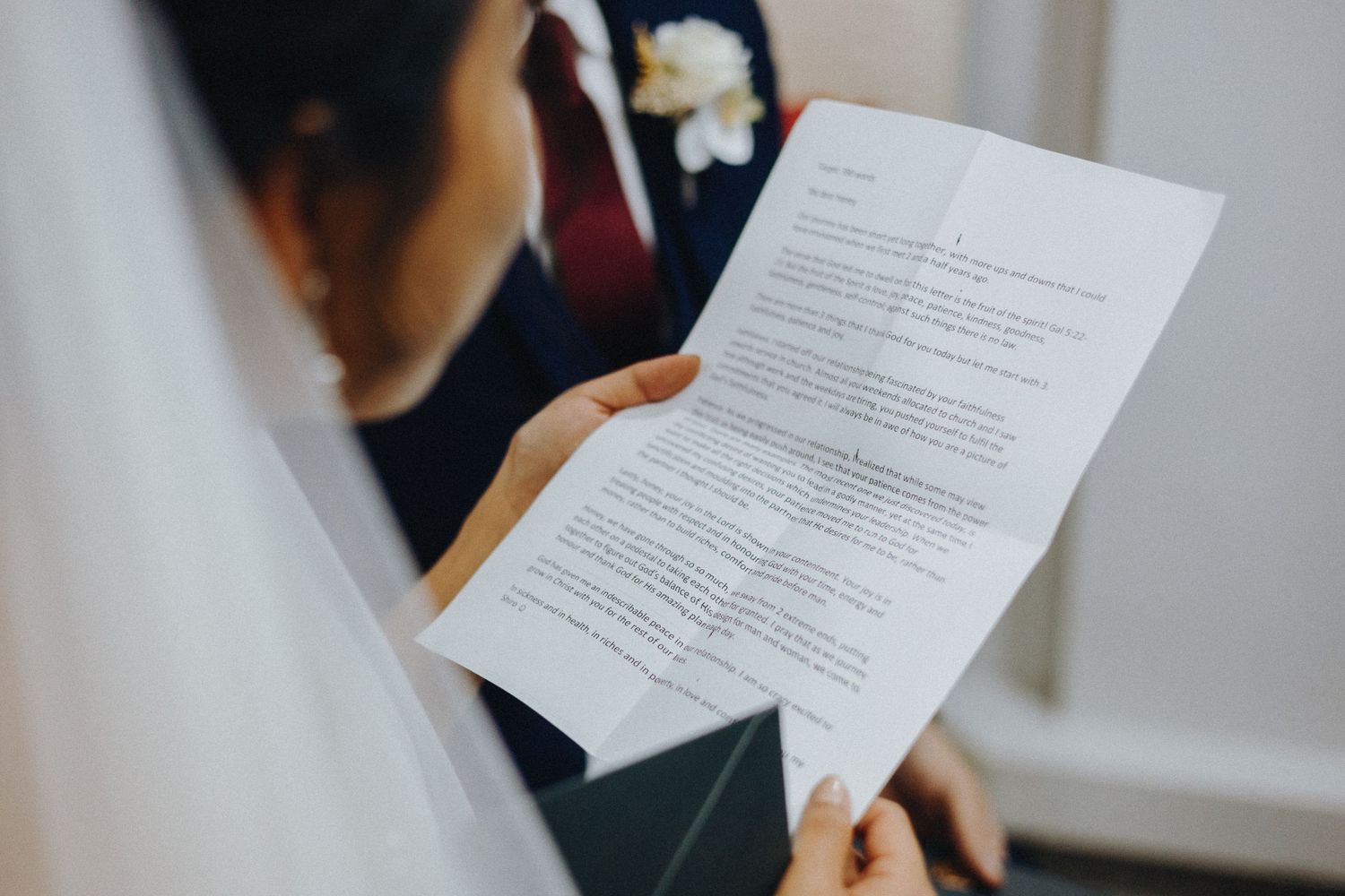 Someone reviews a printed document or resume while sitting near a window in an office setting.