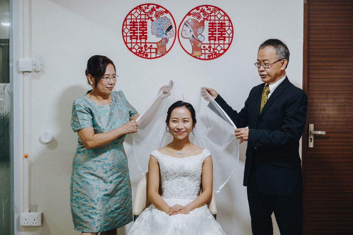 A traditional Chinese wedding celebration features double happiness symbols and joyful moments between family members.