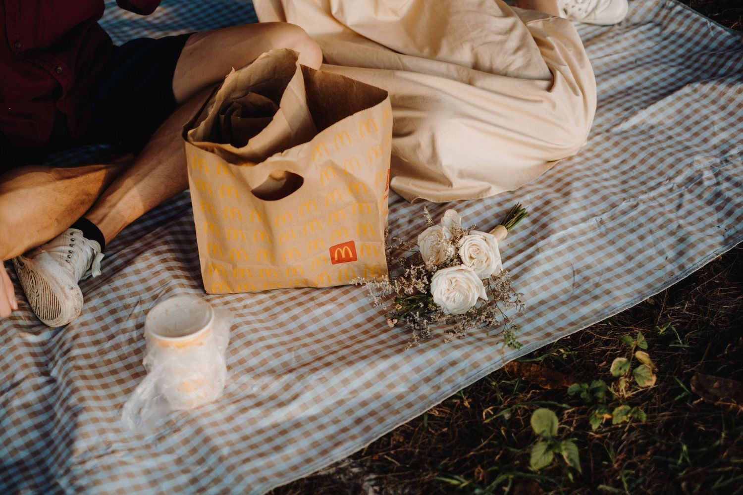 A picnic blanket laid out with snacks and beverages in a forest setting.