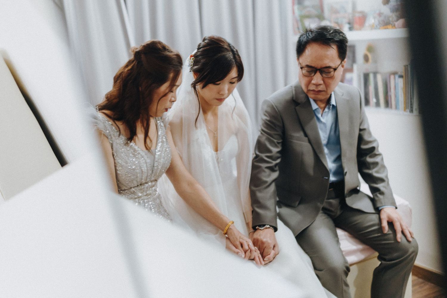 A couple in formal wedding attire sitting together and looking at paperwork or documents.