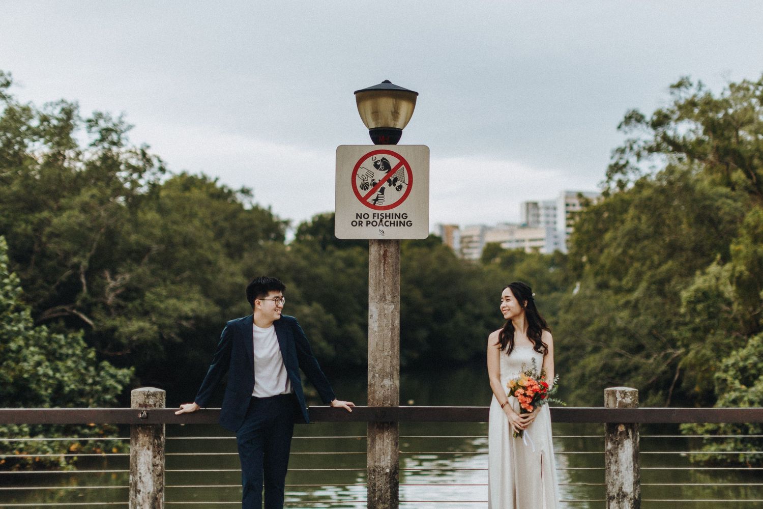 A bride and groom share an intimate moment in front of a rustic wooden railing overlooking a scenic natural landscape.
