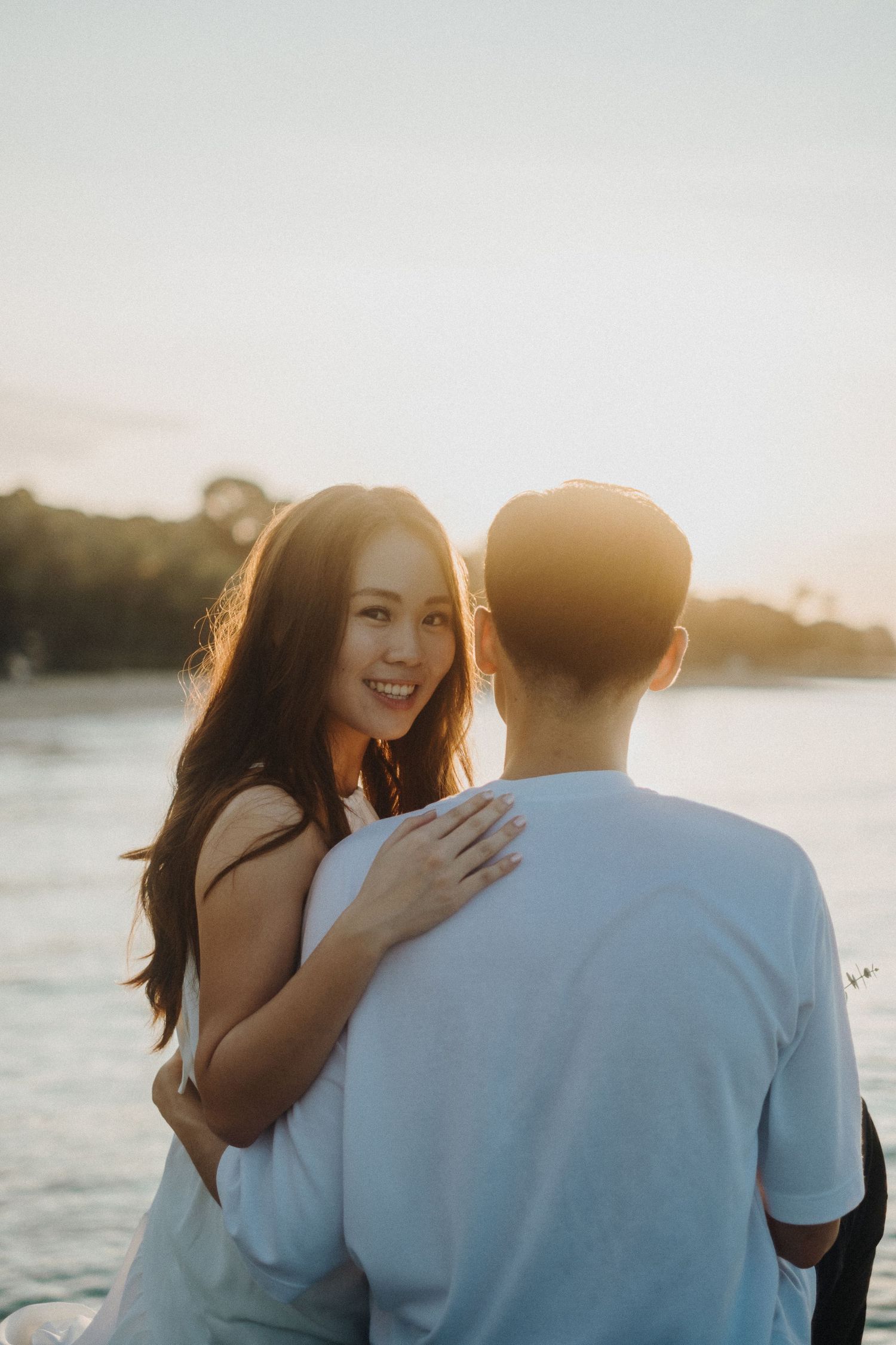Happy couple sharing intimate moment by water during sunset.