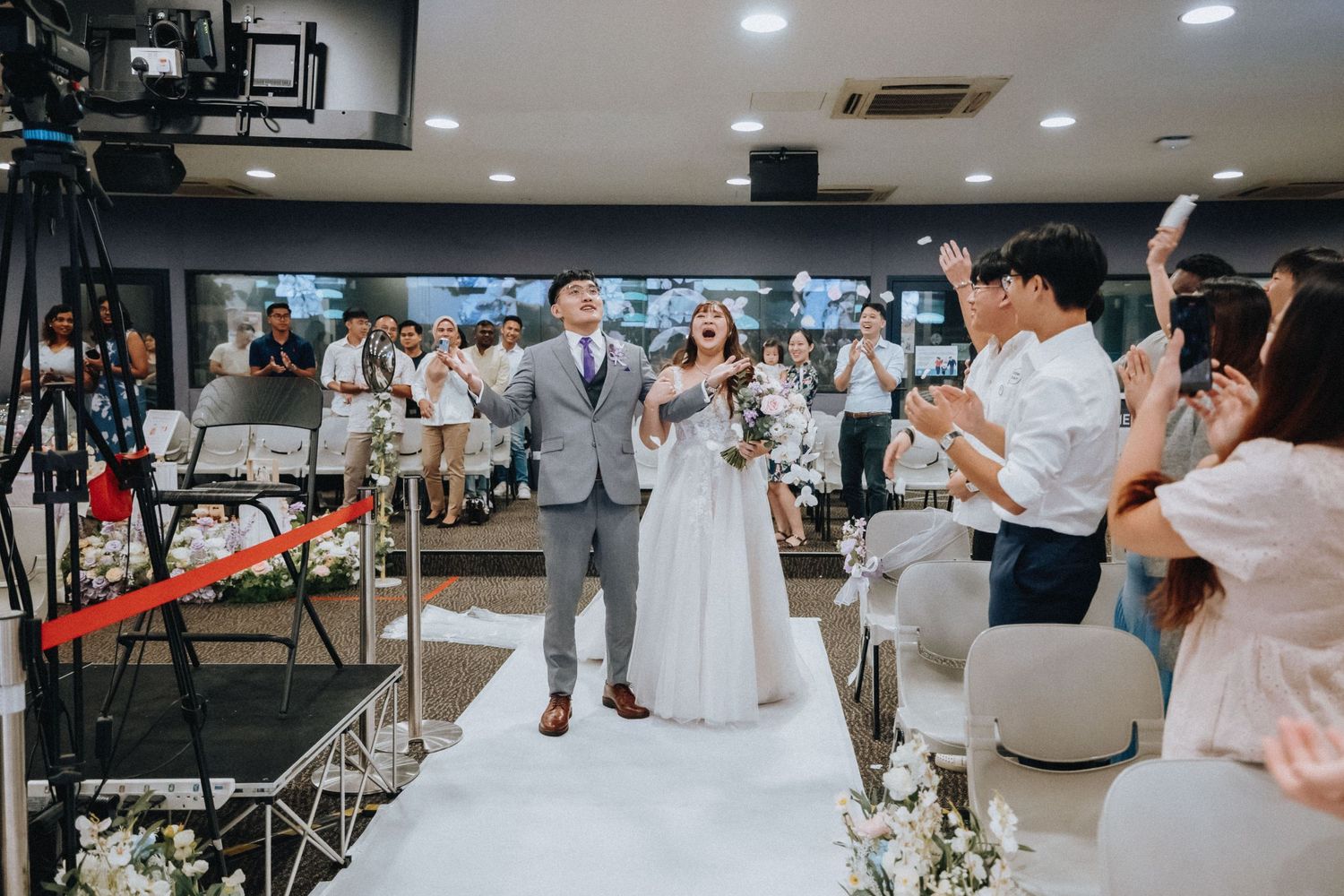 People mingle and socialize in a contemporary event space during what appears to be a wedding reception.