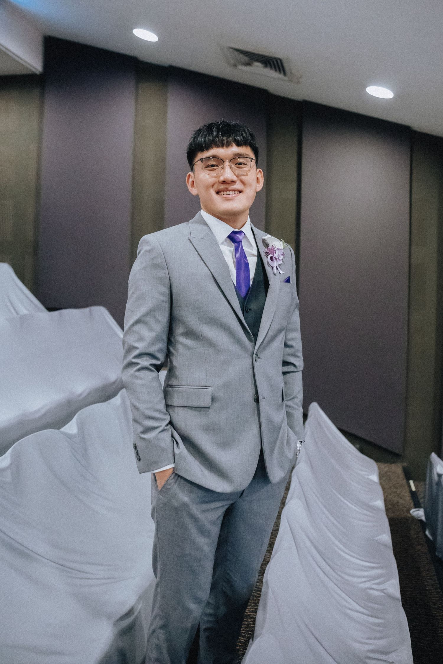 Wedding party members in gray suits posing together in an indoor venue.