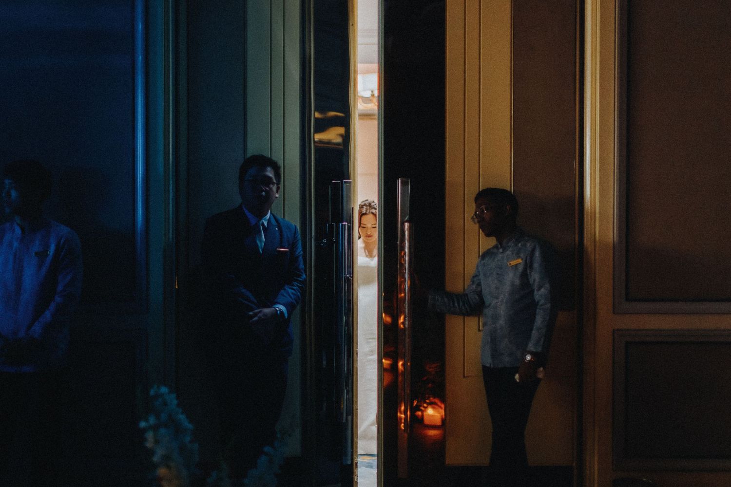 Silhouettes of wedding guests in a dimly lit room during reception.