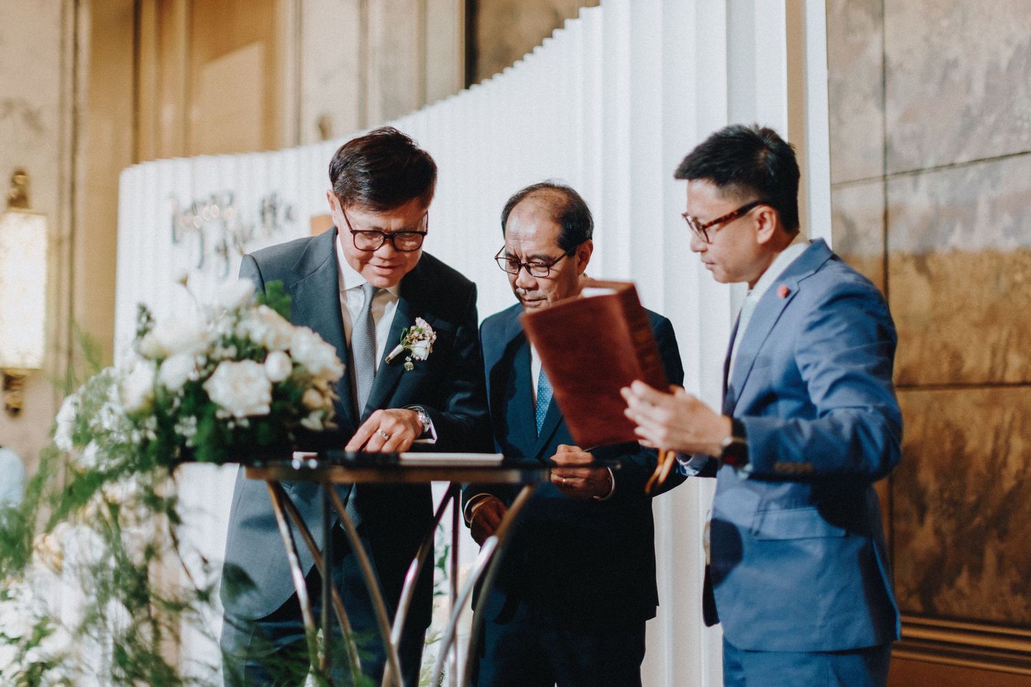 Guests in formal attire checking their phones during wedding reception.