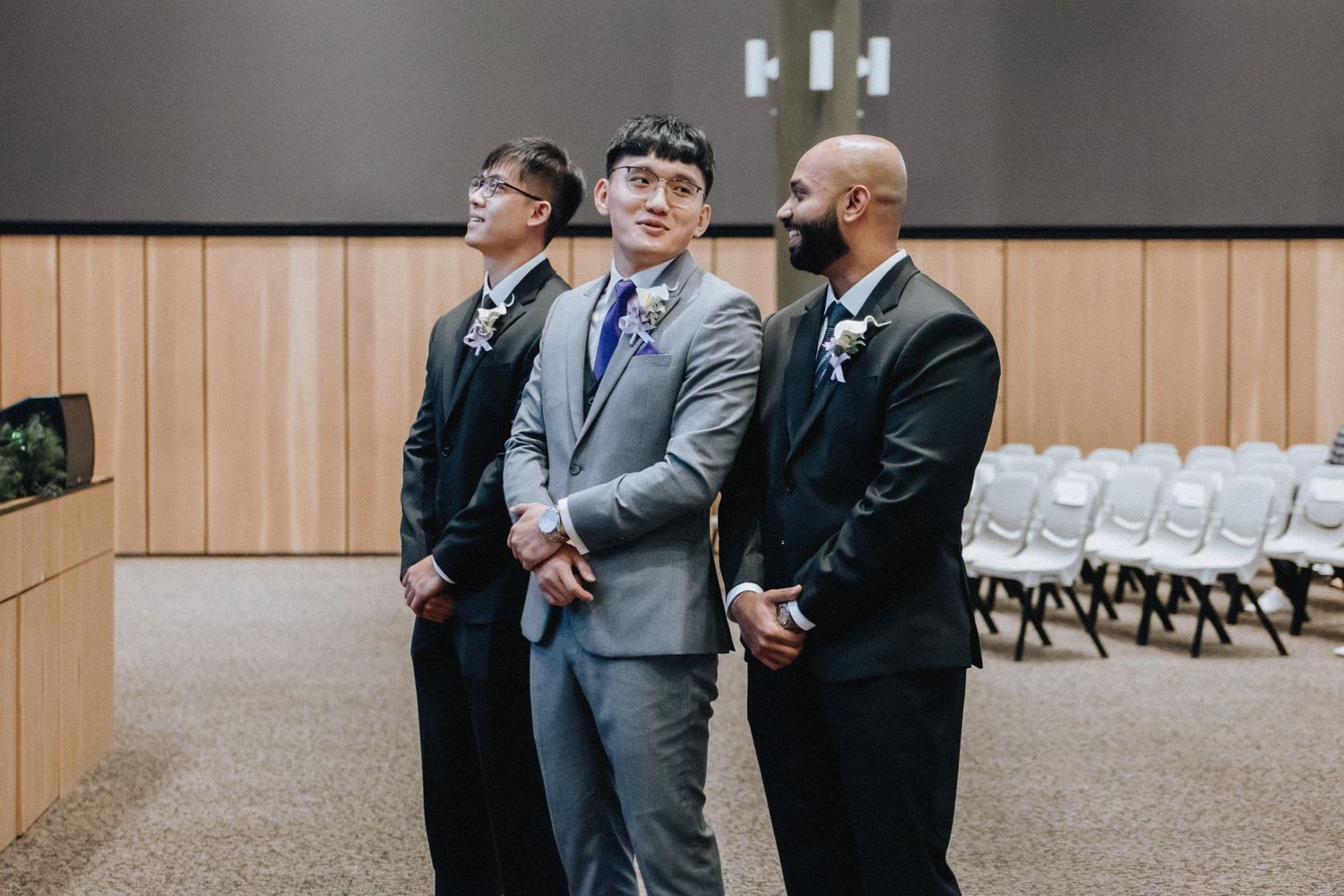 Wedding party members in formal attire gather in a modern venue hallway.