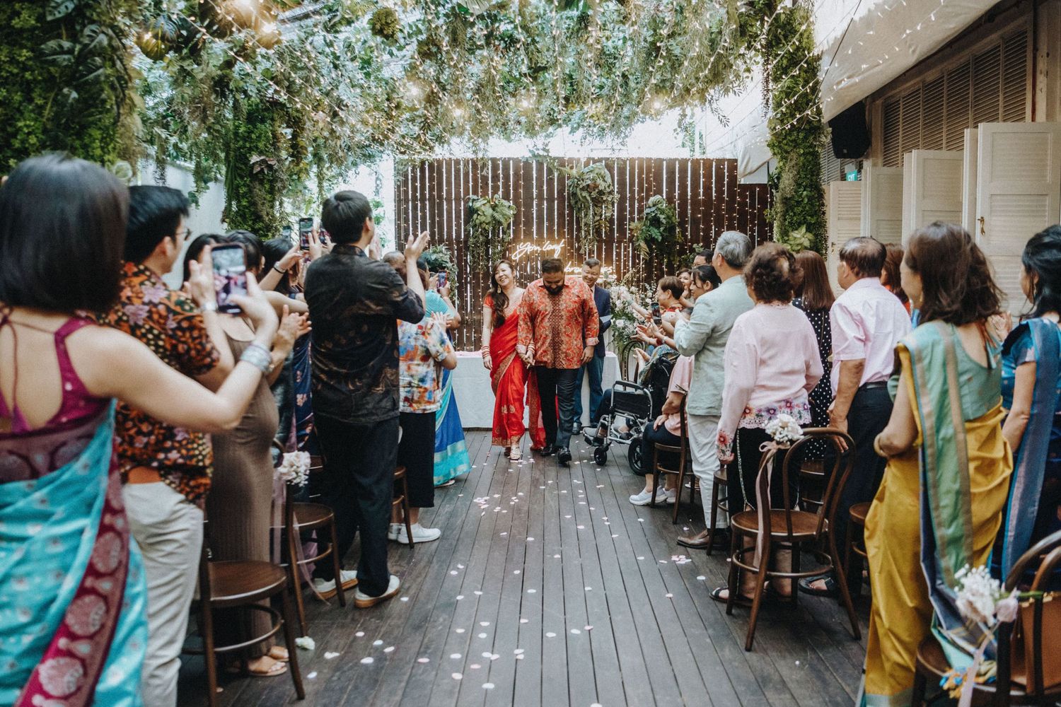 Bride and groom walk down the aisle as guests celebrate at a beautifully decorated garden wedding.