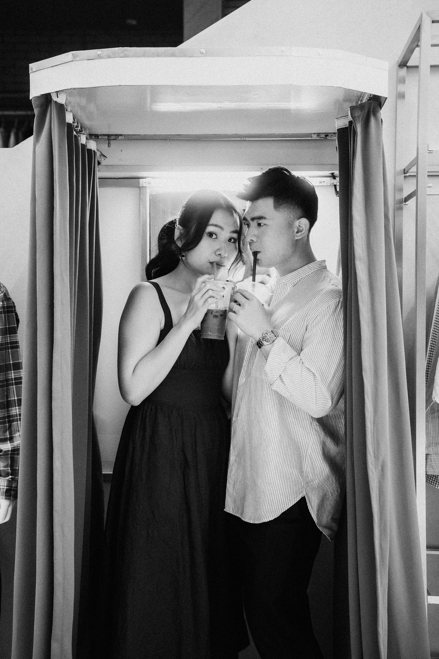 Couple sharing drinks together in a black and white photo booth portrait.