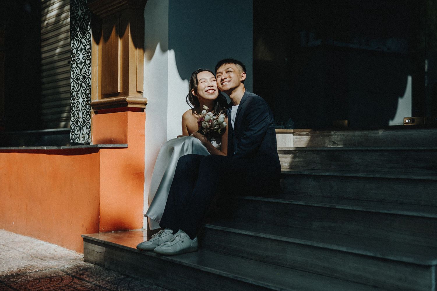 A couple shares a romantic moment on a red staircase during a nighttime photography session.